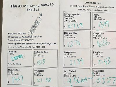 My completed brevet card. Completed brevet card for ACME Grand cycling event showing 12 control points with handwritten arrival/departure times in green ink, distance totals per section, and contact details for Audax UK.