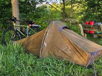 A makeshift roadside pitch using a picnic table bench to attach a tarp to.