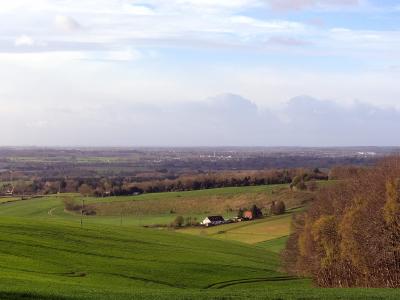 Wide view of rolling green Kent farmland with scattered houses and distant trees.
